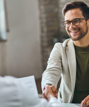 Happy male candidate handshaking with a manager after successful job interview in the office.