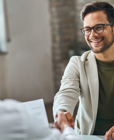 Happy male candidate handshaking with a manager after successful job interview in the office.